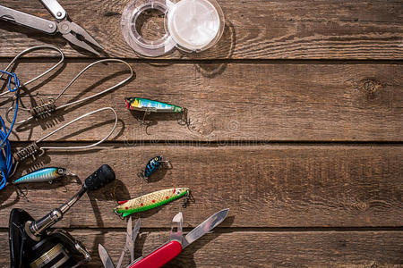 钓鱼用具-钓鱼纺纱,钓鱼线,钩子和诱饵在木制背景。